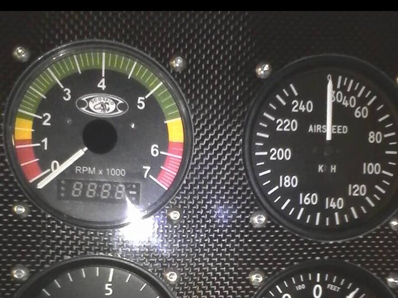 Gros plan sur le tableau de bord de l’avion avec des instruments analogiques affichant les mesures de régime moteur (RPM) et de vitesse.