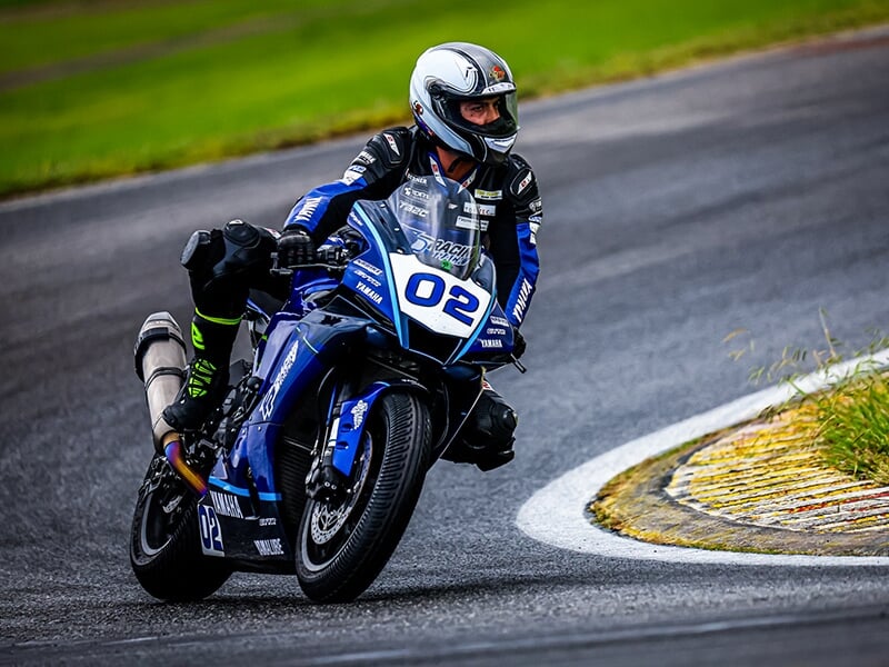 Motard sur une Yamaha bleue n°02 en train de prendre un virage sur une piste de course.