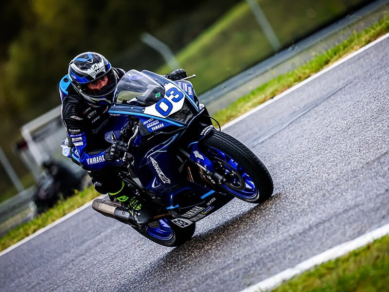 Motard incliné dans un virage, pilotant une Yamaha bleue n°03 avec précision.