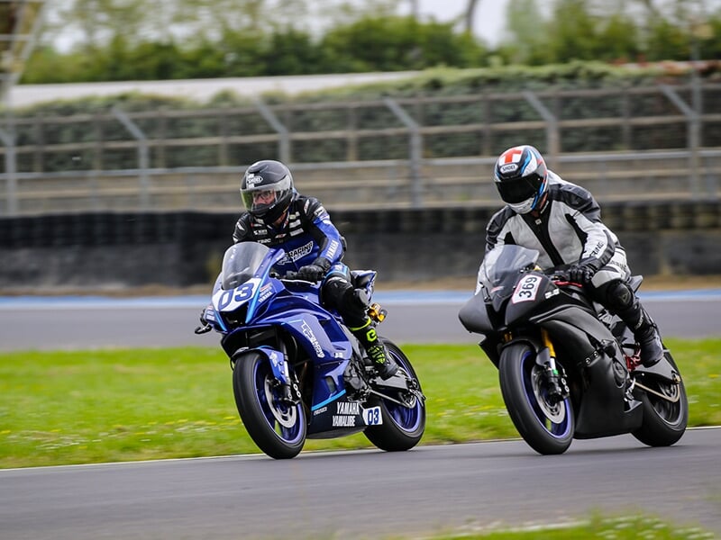 Vue latérale rapprochée d’un motard sur une Yamaha bleue n°03 sur une piste de course.
