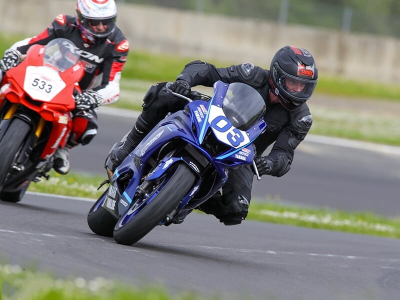 Course intense entre deux motos, le motard sur la Yamaha n°03 serrant de près son adversaire.