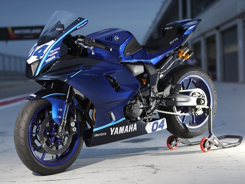 plan statique d’une Yamaha de course stationnée sur un paddock, mise en valeur par un éclairage soigné.