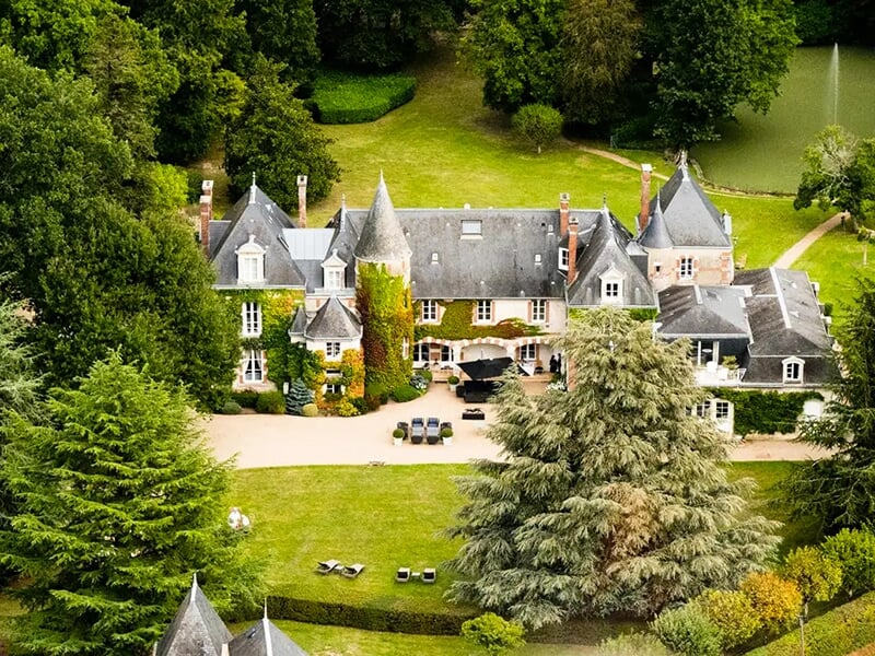 Manoir entouré de grands arbres et d'une pelouse bien entretenue, avec une ambiance chaleureuse et élégante.