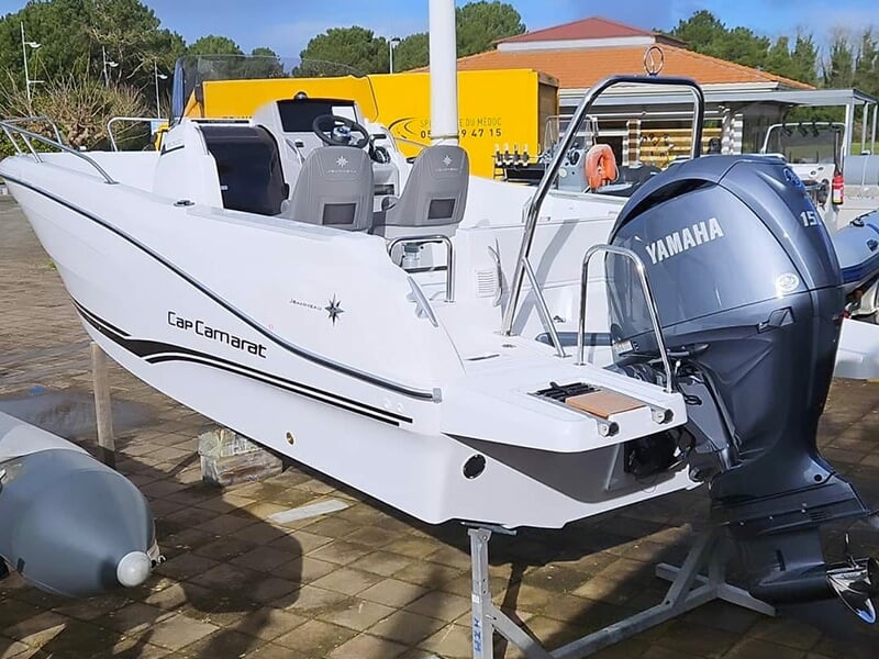 Petit bateau à moteur blanc de type Cap Camarat, équipé d’un moteur Yamaha, posé sur un support à terre.