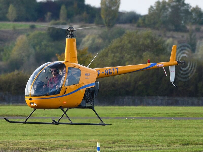 un hélicoptère robinson R22 orange en plein décollage