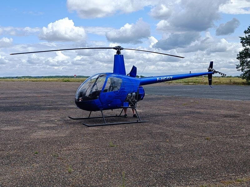 un robinson r22 bleu sur une piste de décollage d'hélicoptère