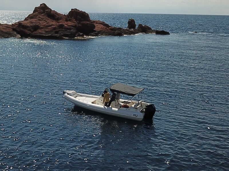 Bateau flottant près d'îlots rocheux en pleine mer, sous un ciel dégagé et une mer calme.