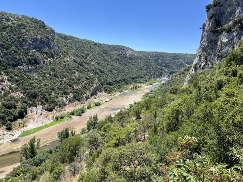 Vue panoramique des gorges du Verdon, entourées de collines sous un ciel bleu clair.