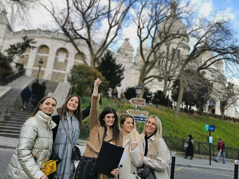 Cinq jeunes femmes posent joyeusement devant la basilique du Sacré-Cœur à Montmartre.