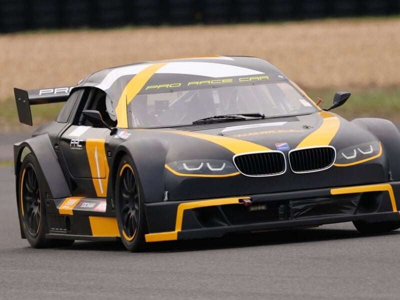 Gros plan sur une Mitjet 2L orange et noire en pleine course sur un circuit