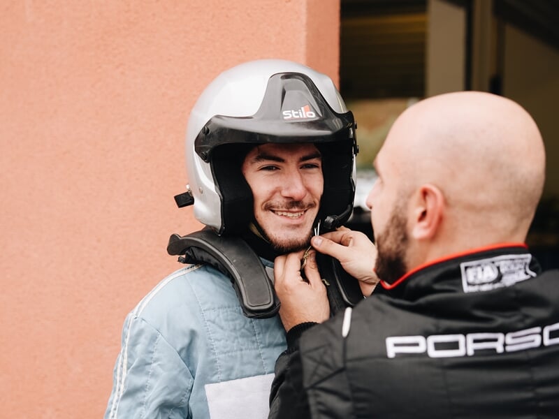 Un homme se faisant aider pour mettre son casque sur circuit de voiture