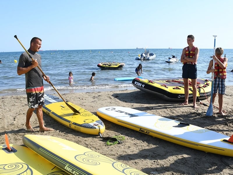 Un cours de paddle sur la plage avec plusieurs planches et baigneurs en arrière plan