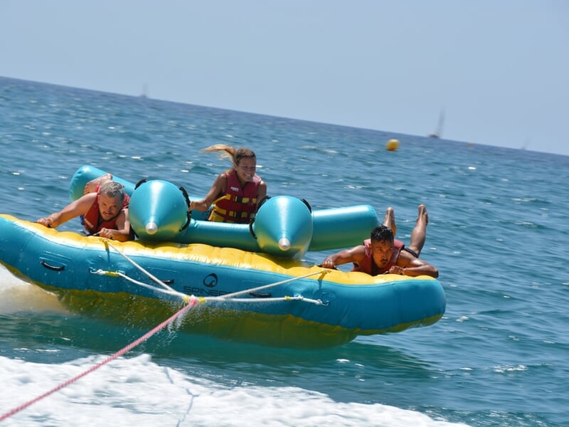 Trois personne sur une bouée tractée en pleine mer
