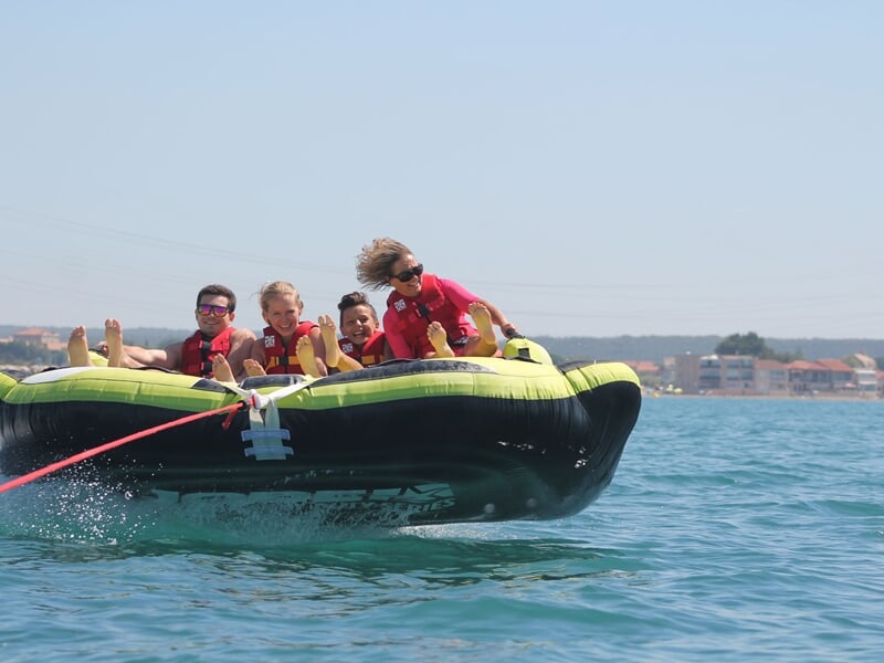 Groupe de personnes sur une bouée tractée avec côte en arrière plan