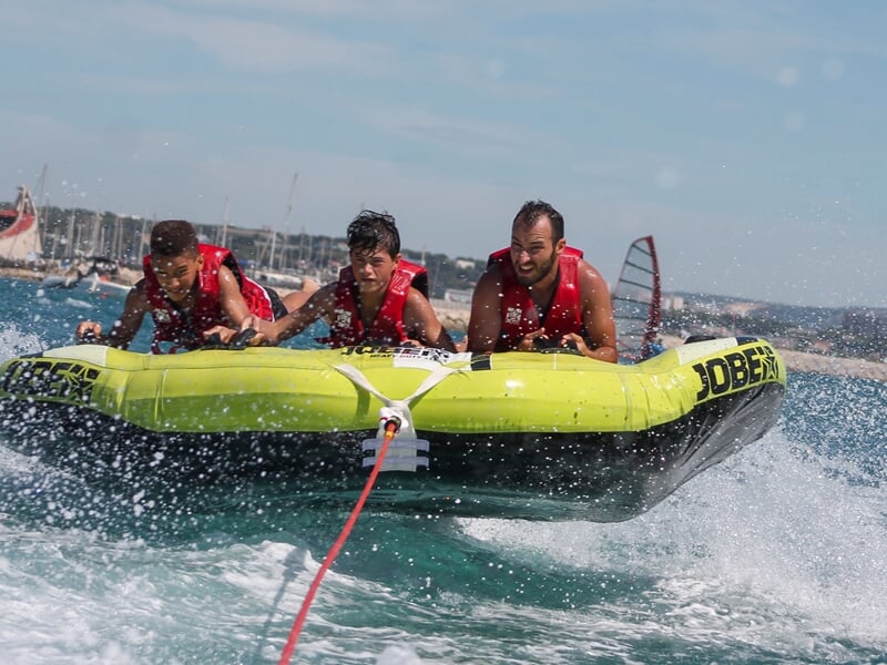 Trois personnes sur une bouée tractée en pleine mer