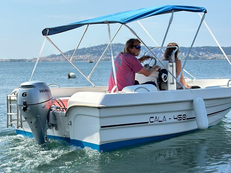 Deux personnes à bord d'un bateau sans permis au milieu de l'eau avec côte au loin