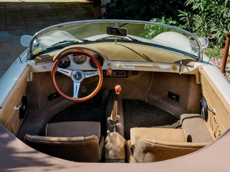 Un aperçu de l’intérieur d’une voiture ancienne, avec un tableau de bord simple et raffiné, des matériaux nobles et un volant d’époque.
