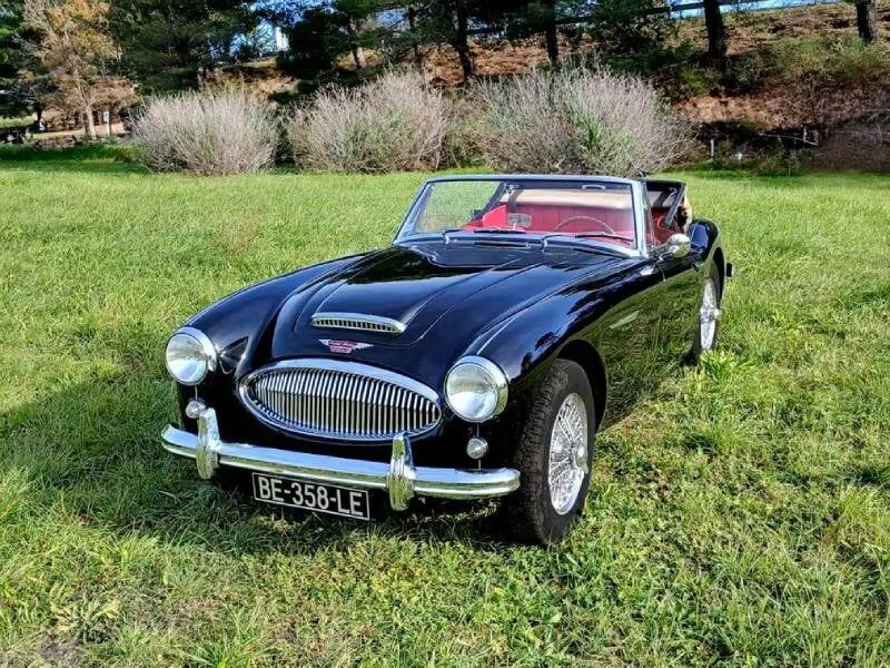 Une voiture classique noire avec une allure élégante et sportive, capturée dans un décor pittoresque, probablement en pleine nature ou en ville.