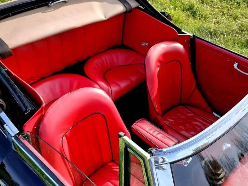 Intérieur d'une voiture décapotable ancienne avec sellerie en cuir rouge vif, coutures noires contrastantes et finition soignée