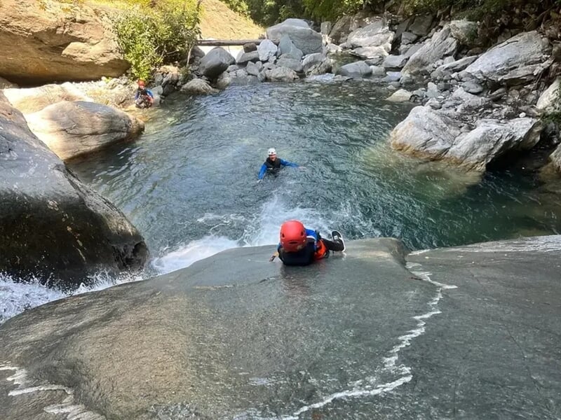 Groupe de personne pratiquant le canyoning avec glissage sur un toboggan naturel