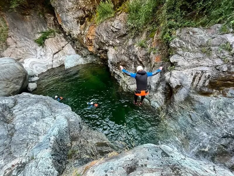 Une personne faisant un saut dans l'eau au milieu des rochers