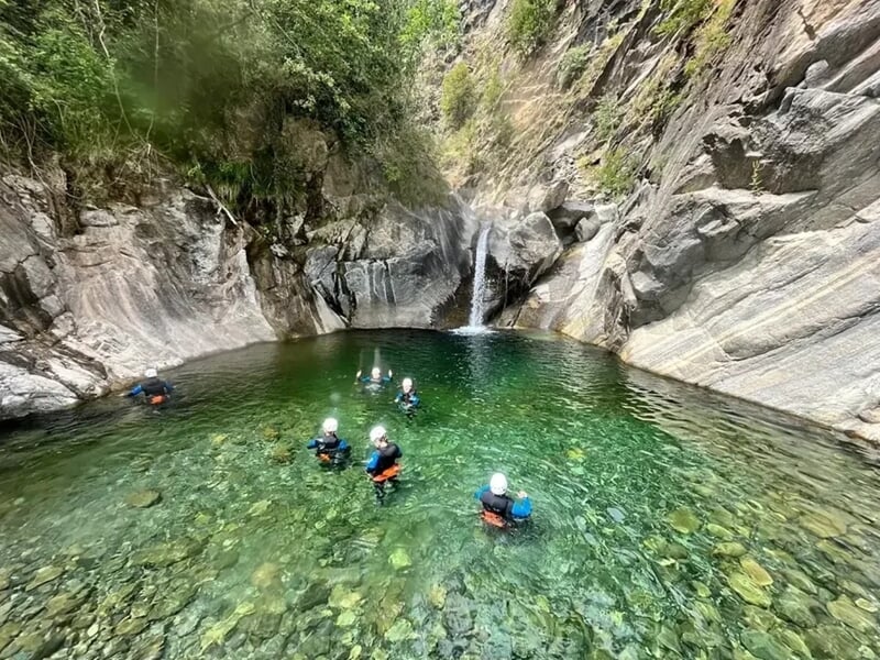 Groupe de personne pratiquant le canyoning au milieu de l'eau