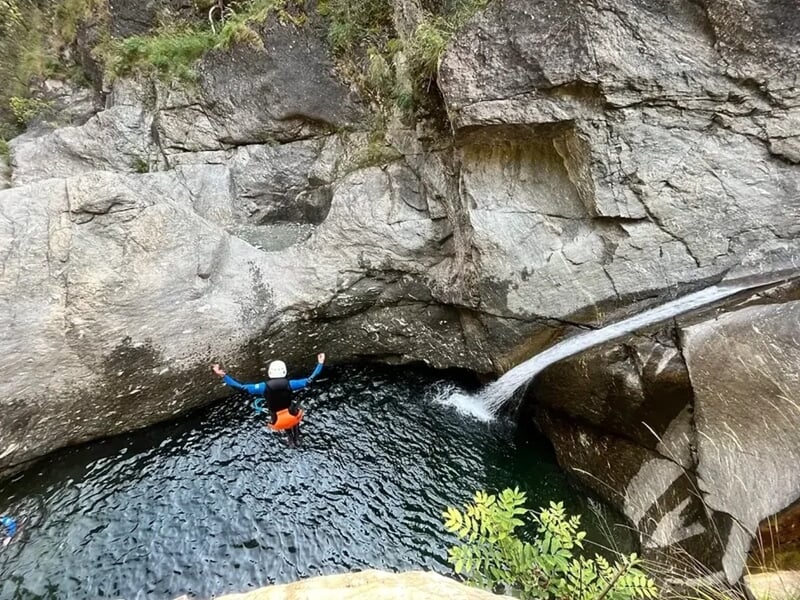 Une personne faisant un saut dans l'eau au milieu des rochers