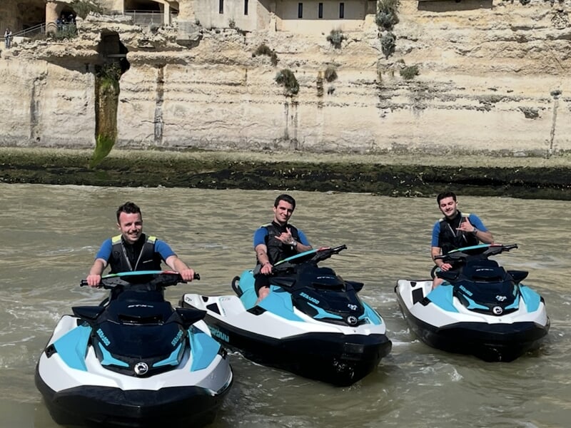 Groupe de trois hommes posant en jet ski devant les grottes du Régulus
