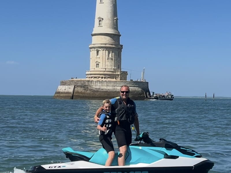 Un père et son fils sur un jet ski devant le phare de Cordouan