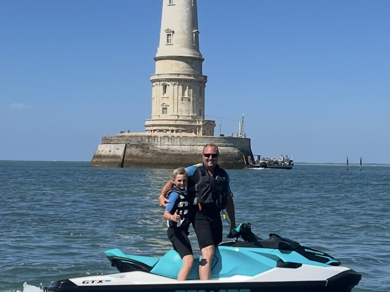 Un père et son fils sur un jet ski devant le phare de Cordouan