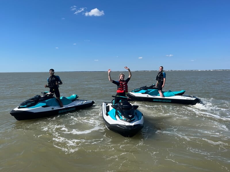 Groupe de 3 personnes posant chacun sur un jet ski en mer