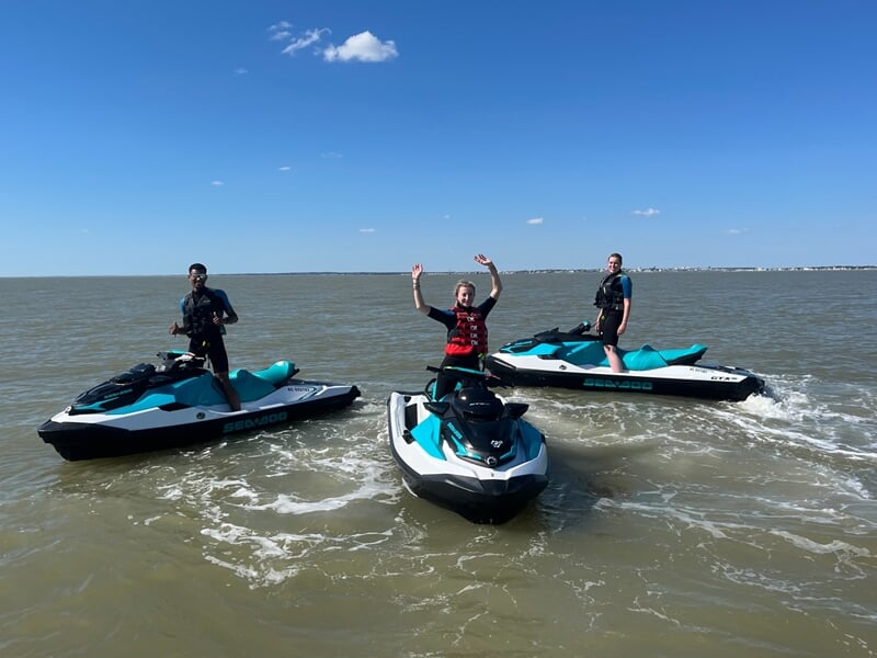 Groupe de 3 personnes posant chacun sur un jet ski en mer