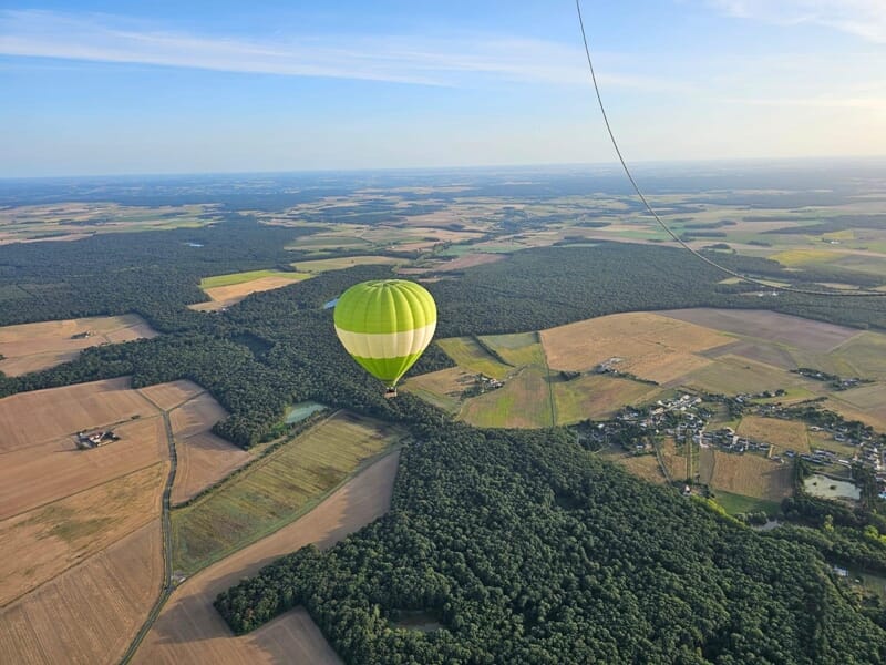 Une montgolfière volant au dessus des champs avec un ciel bleu