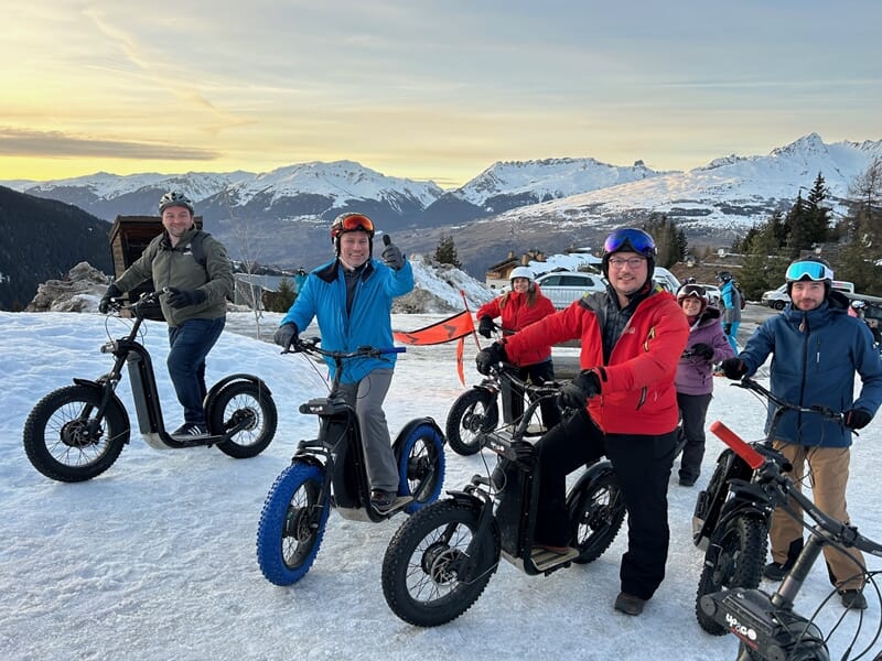 Groupe de personnes en trottinette électrique dans un paysage de montagne enneigée