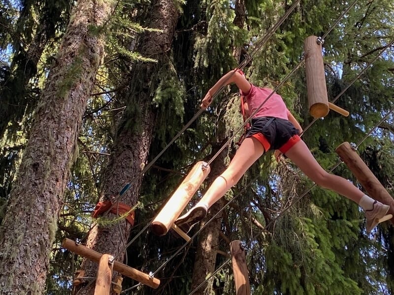 Une femme effectuant un parcours d'accrobranche dans les arbres