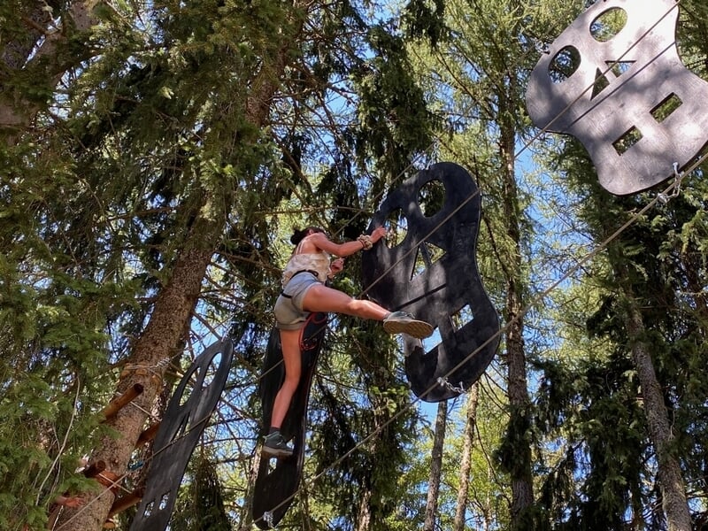 Une femme effectuant un parcours d'accrobranche dans les arbres