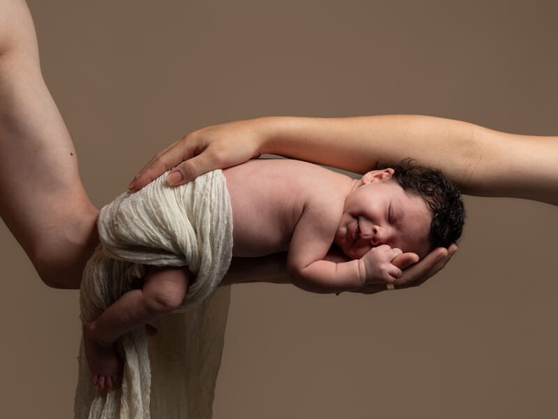 Nouveau-né couché sur le bras de son père et protégé par le bras de sa mère