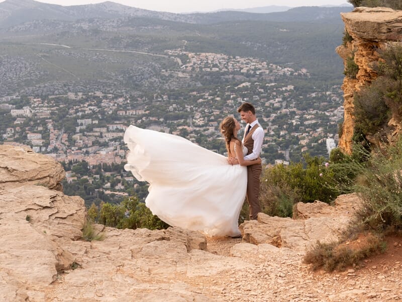 Couple posant sur une falaise devant une ville de mediterrannée