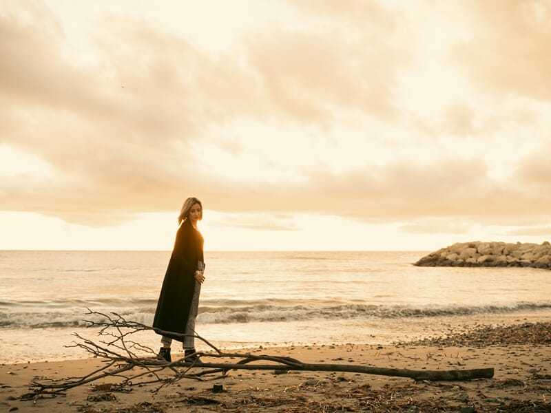 Une femme au bord de la mer au coucher du soleil