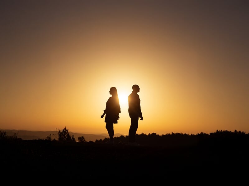 Deux personnes à contre-jour devant le soleil couchant