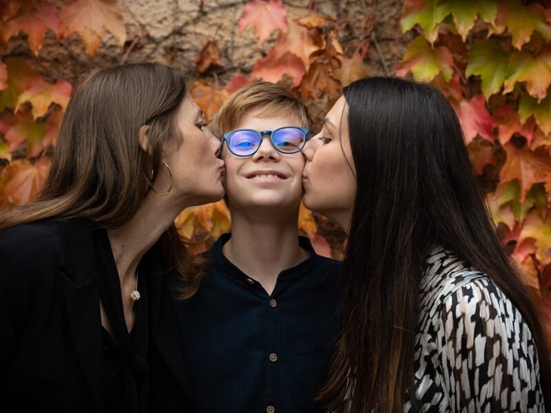 Famille de deux femmes et un adolescent se faisant une bise devant des feuilles d'automne