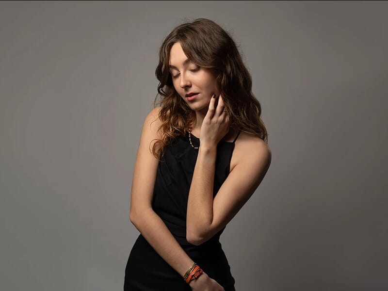 Photo studio d'une jeune femme brume en robe noire sur fond gris