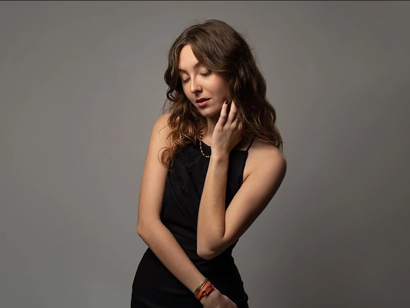 Photo studio d'une jeune femme brume en robe noire sur fond gris