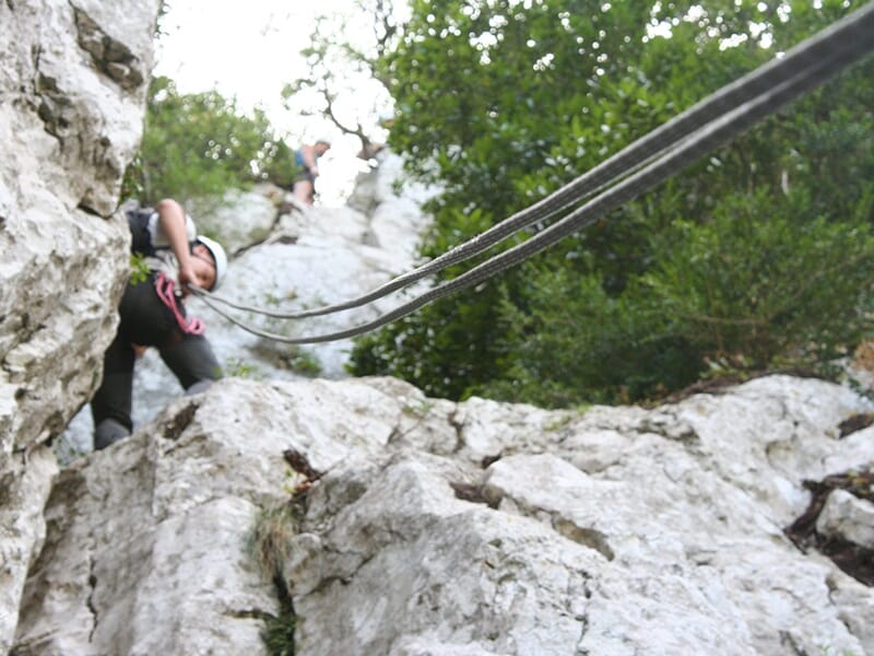 Jeune fille équipée d’un casque et d’un baudrier, prête à glisser sur une tyrolienne au cœur de la garrigue.