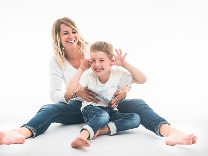 Maman et fils en jeans, rires et grimaces en studio.