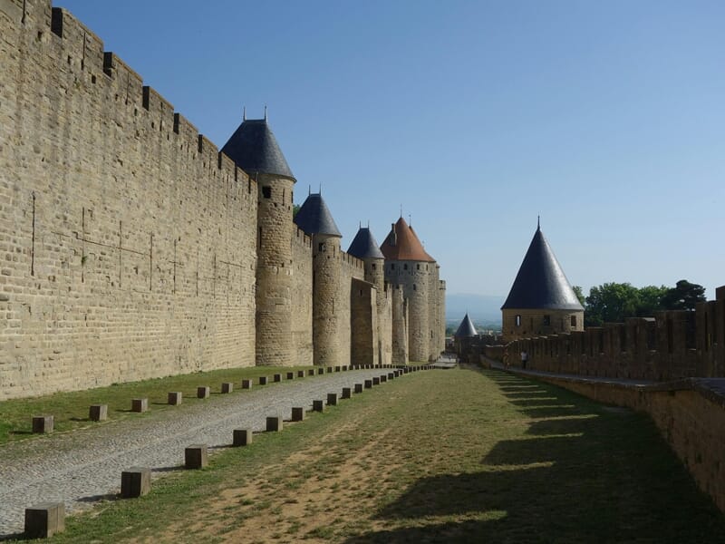 Vue dégagée des remparts et tours de la Cité de Carcassonne sous un ciel bleu.