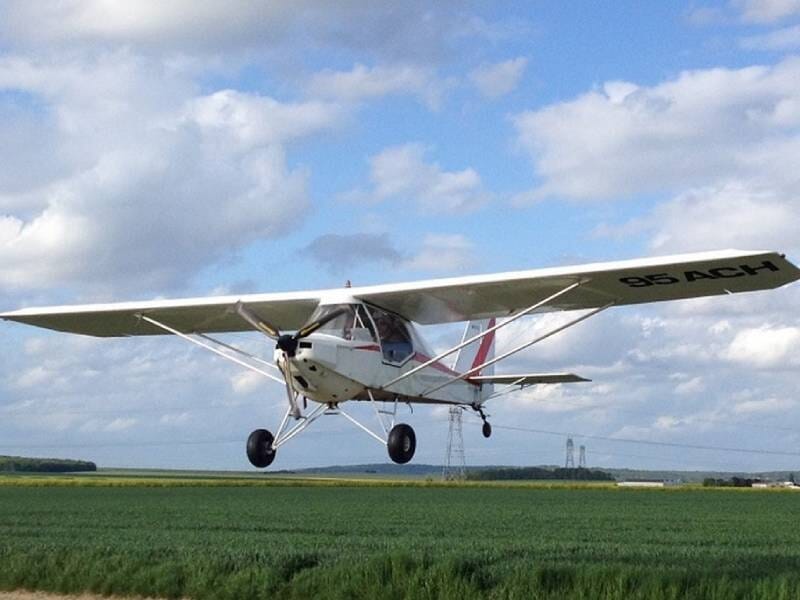 Avion ULM J300 en train de décoller, il est blanc avec des bandes rouges