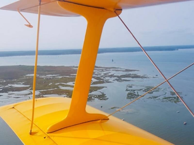 Vue aérienne sur l'eau depuis l'aile d'un ULM biplan jaune