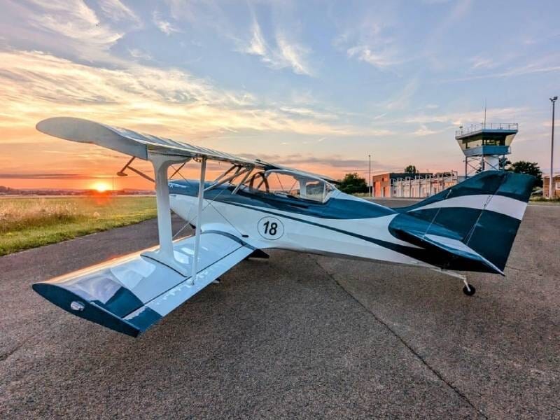 FK12 Comet bleu marine et blanc vu de côté avec un coucher de soleil en fond