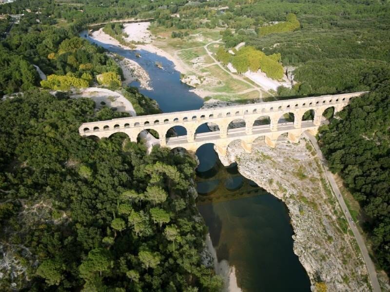 Vue aérienne sur le pont du Gard, un cours d'eau passe en dessous et il est entouré de verdure